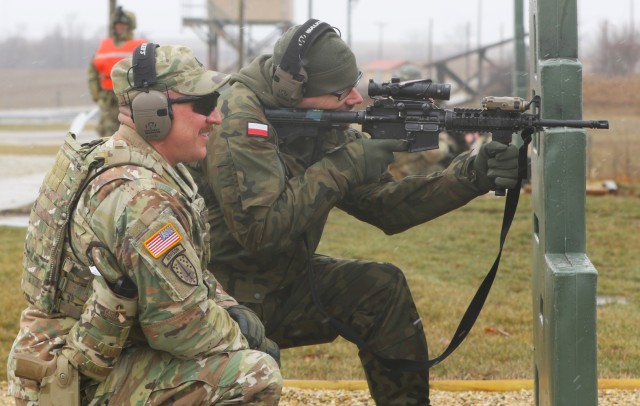 Illinois Army National Guard Capt. Drew Weaver discusses the firing of the M-4 with Maj. Andrew Majcherek of the Polish Territorial Defense Force on the range at the Illinois Army National Guard&#39;s Marseilles Training Area. Weaver was one of four Illinois National Guard Soldiers awarded the bronze Polish Armed Forces Medal on March 25, 2023, for their work training Polish Territorial Defense Force Soldiers in Poland in May and June 2022.
