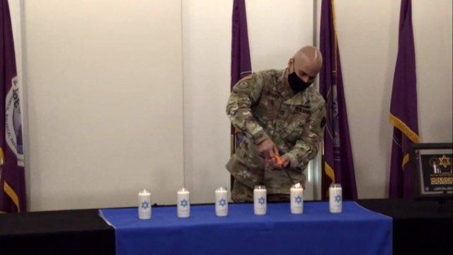 Soldier lights a candle in remembrance of Holocaust victims.