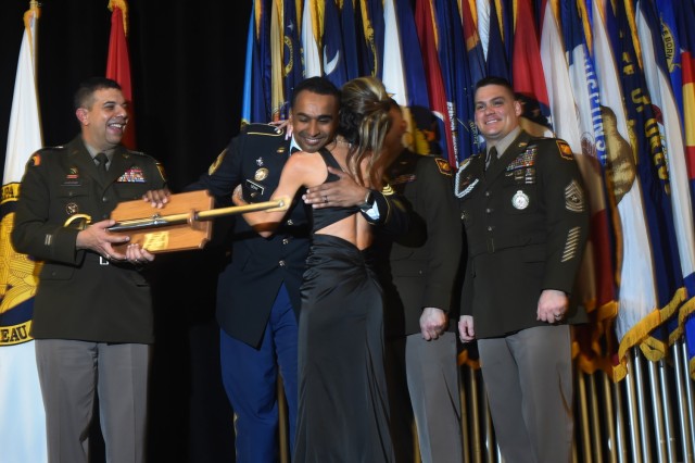 Master Sgt. Christopher Sehy, a recruiter with the Utah Army National Guard, embraces his wife, Crystal, as he receives the Army National Guard Recruiting and Retention Noncommissioned Officer of the Year award from Maj. Gen. John Andonie, left, deputy director of the Army National Guard, during the Director’s Strength Maintenance Awards and Conference in New Orleans, Louisiana, March 23, 2023. The conference brings together Army Guard recruiting team chiefs and the top Army Guard recruiters for training sessions and networking opportunities to tackle the challenges of recruiting. (U.S. Army Photo by Sgt. 1st Class Jon Soucy)