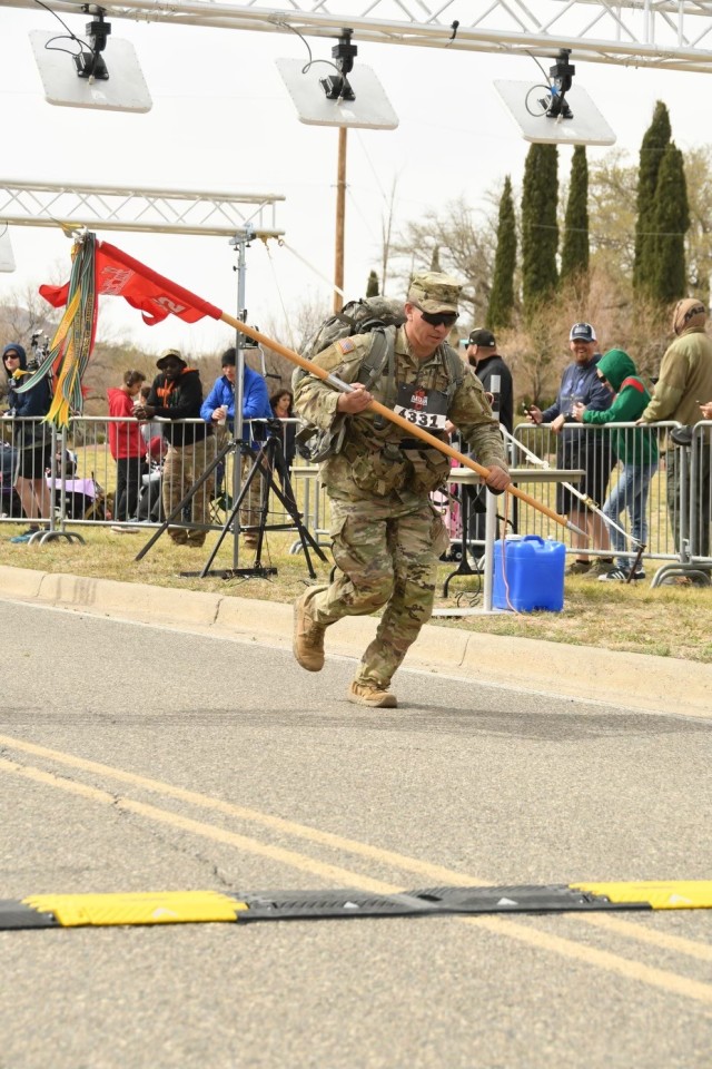 U.S. Army South Soldier, Sgt. Aaron Thomas, a plans and analysis team leader in the 512th Geospatial Engineer Detachment, carries his detachment guidon across the finish line of the Bataan Memorial Death March, on the White Sands Missile Range, New Mexico, March 19, 2023. According to The Bataan Memorial Death March website, the event is a 26.2-mile ruck march to remember the roughly 75,000 U.S. and Filipino service members who became prisoners of war in the Philippines during World War II and were forced to march approximately 65 miles through the jungle to confinement camps by their Japanese captors. (Courtesy photo)