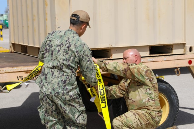U.S. Army Staff Sgt. Matthew Zink, aviation quality control, 5th Battalion, 159th Aviation Regiment, 244th Expeditionary Combat Aviation Brigade, and Navy Seaman Lloyd Cuesto, logistics specialist, Naval Supply Systems Command Fleet Logistics Center - Rota, secure aviation equipment on transport vehicles for Defender 23 in Rota, Spain, April 6, 2023.