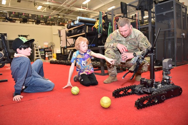 Sgt. Tyler Hassell, with the 763rd Ordnance Company, explains some of the capabilities of the Common Robotics System – Individual robot to Wood Elementary School third graders Andrew Histed and Bentley Holcomb, on Friday at the company’s...