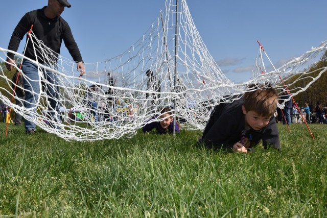 Elliot Felker, age 9, and Charlotte Felker, age 5, low crawl under netting at an obstacle course during Saturday’s Month of the Military Child Palooza on Gerlach Field.