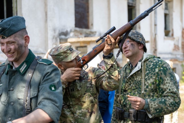 A U.S. Army Soldier aims down the sights of a replica rifle with Bulgarian volunteer