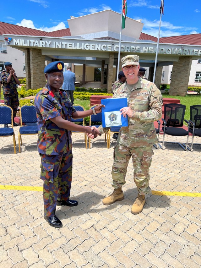 Maj. Joe Huitt of Army Cyber Command's Joint Force Headquarters-Cyber (Army) presents an ARCYBER memento to Col. D.O. Owili, Cyber Branch director, Kenya Defense Forces Directorate of Military Intelligence, during the Kenyan Cyber Workshop, at the Kenyan Military Intelligence Corps Headquarters in Nairobi, Kenya. The workshop, conducted April 24-26, 2023, was U.S. Africa Command's first such event with Kenyan forces. (Courtesy photo)
