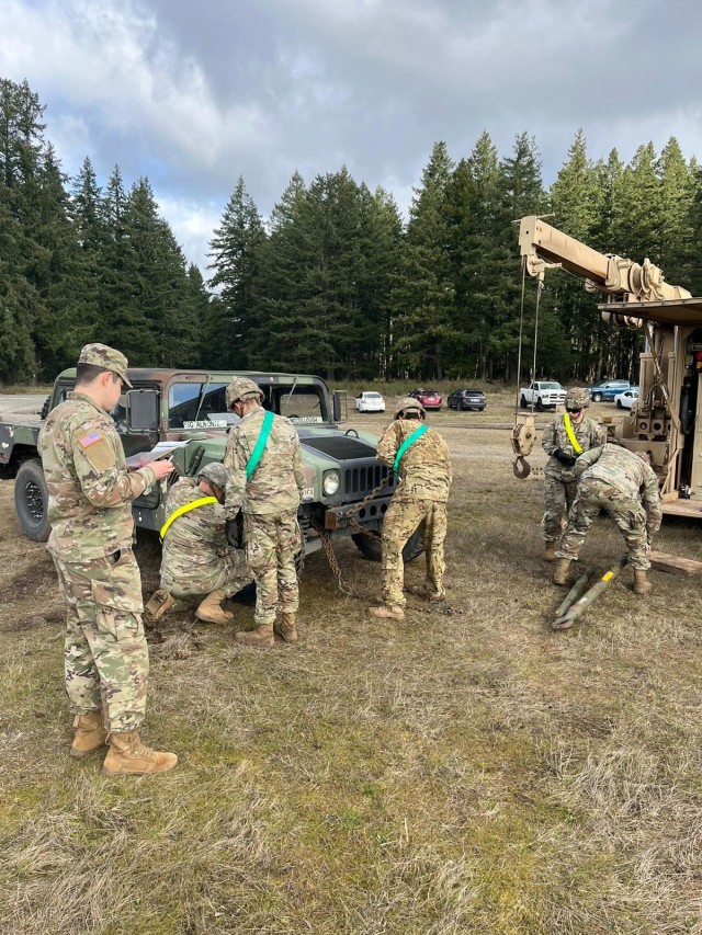 Capt. Max Bostick grades members of 657th Forward Support Company as they prepare their Humvee for tire change during a Sustainment Best By competition Feb. 10, 2021, at Joint Base Lewis-McChord, Washington.