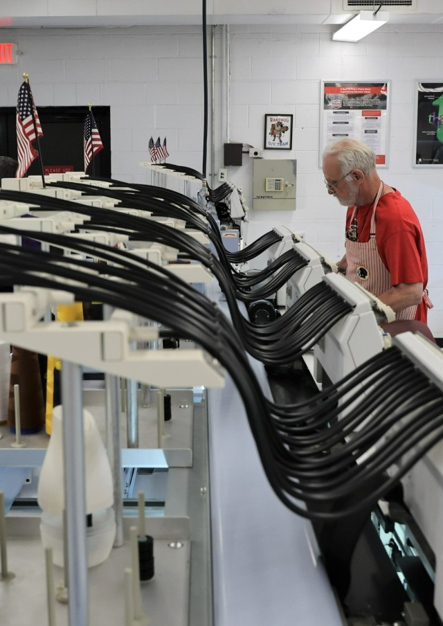 A worker at the Fort Knox Exchange Name Tape Plant loads camouflage tape into the embroidery machine May 9, 2023 in preparation for printing service members’ names onto it.