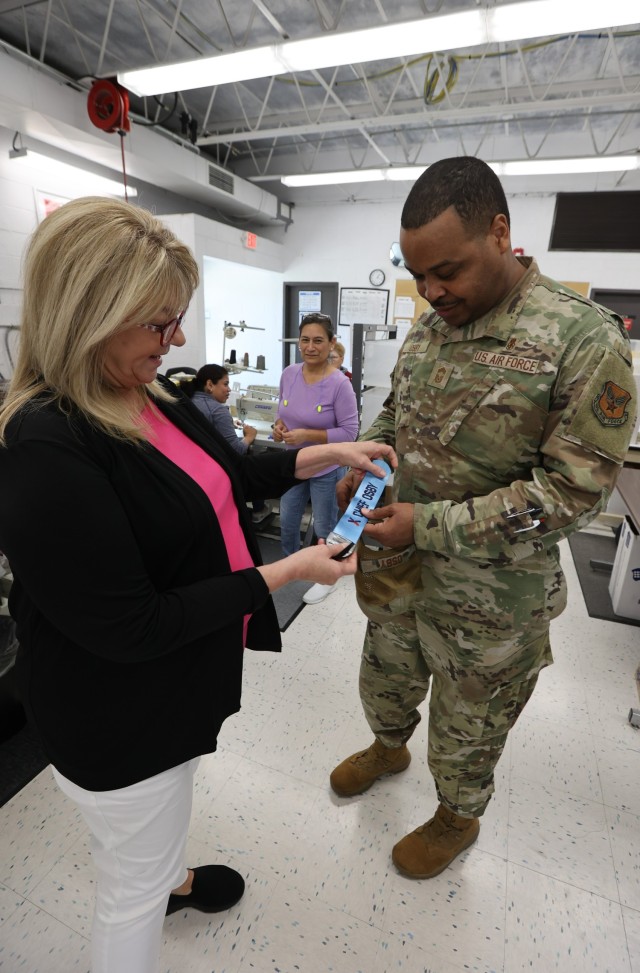 Fort Knox Exchange Name Tape Plant manager Teresa Green presents AAFES senior enlisted advisor Chief Master Sgt. Kevin Osby with a luggage tag embroidered for him during his visit to the facility May 10, 2023.