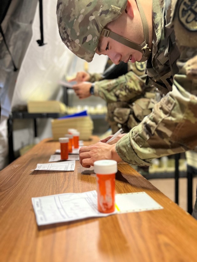During a field hospital practical exercise, Capt Jin Nam Ahn, a pharmacy officer from Walter Reed National Military Medical Center, prioritizes and checks medication orders in the outpatient pharmacy for distribution to patients discharging from the intermediate care ward. A pharmacist check ensures patient safety and compliance with regulations that govern medication dispensing. (Courtesy photo).