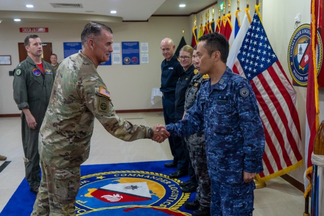 Gen. Charles Flynn, commanding general of U.S. Army Pacific, left, presents his challenge coin to Japanese Maritime Self-Defense Force Cmdr. Yoichi Kabasawa and naval officers from the United Kingdom, New Zealand, and Australia during his tour of...