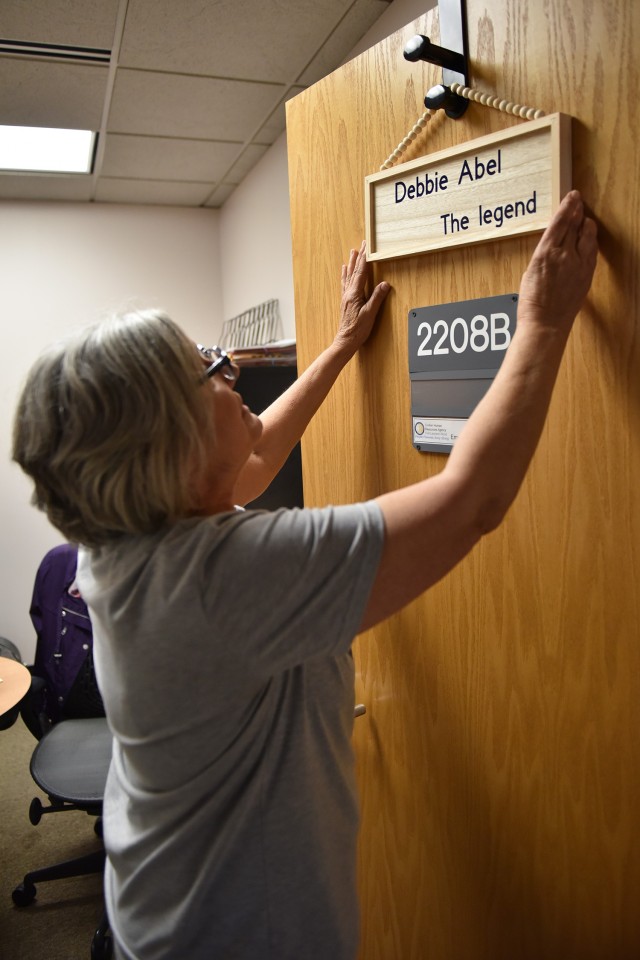 Deborah Abel, human resources specialist at Fort Leonard Wood’s Civilian Personnel Advisory Center, adjusts her name sign on her office door. She earned the nickname, “The Legend,” because she has been at CPAC longer than anybody else currently in the office.  Abel will retire next week after serving for 33 years as a Department of the Army civilian. 