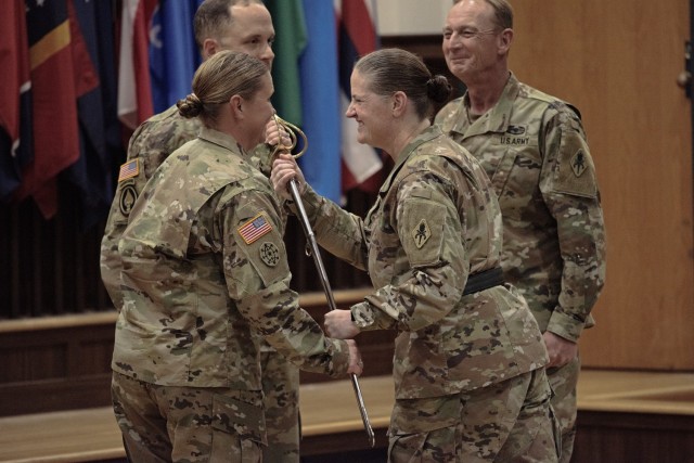 Incoming U.S. Army Military Police School Regimental Chief Warrant Officer 4 Angela Rulewich (left) accepts the ceremonial USAMPS saber from Brig. Gen. Sarah Albrycht, USAMPS commandant, as outgoing USAMPS Regimental Chief Warrant Officer 5 Mark Arnold (right) looks on during a change-of-responsibility ceremony this afternoon in Lincoln Hall Auditorium. 