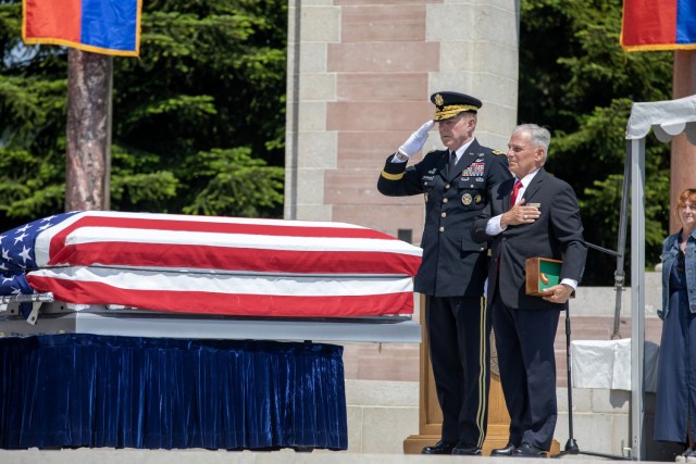 Gen. James C. McConville, the U.S. Army Chief of Staff (left) and Bert Caloud, the Oise-Aisne American Cemetery superintendent, salute after placing a Purple Heart on the casket of the WWI unknown soldier during a burial ceremony at Oise-Aisne American Cemetery.