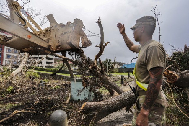 Sgt. Joseph Mafnas of the 1224th Engineer Support Company, Guam National Guard, helps a High Mobility Engineer Excavator (HMEE) operator remove debris after Typhoon Mawar in Guam June 2, 2023. 