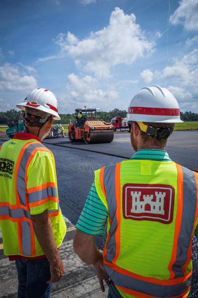 Matthew Hoyle (right), U.S. Army Corps of Engineers materials engineer, oversees asphalt placement at Hunter Army Airfield, June 2. As a materials engineer, Hoyle reviews the methods, approach, quality of work, designs and asphalt mixtures to ensure proper asphalt density and USACE runway standardization requirements.