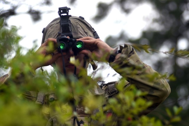 Spc. Grant Simmons, a combat engineer with the 1123rd Engineer Company (Sapper), Kentucky Army National Guard, uses binoculars to search for enemy movement after his unit was attacked during a training rotation at the Joint Readiness Training...