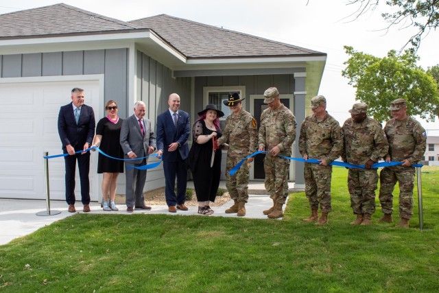 Cavalry Family Housing staff, Lendlease management and III Armored Corps and Fort Cavazos leadership watch as Allison and Spc. Grant Boshaw, 1st Air Cavalry Brigade, 1st Cavalry Division, cut the ribbon outside their brand-new home June 16, 2023, at Fort Cavazos, Texas. The Boshaw family is the first to receive the keys to a new home. (U.S. Army photo by Samantha Harms, Fort Cavazos Public Affairs)