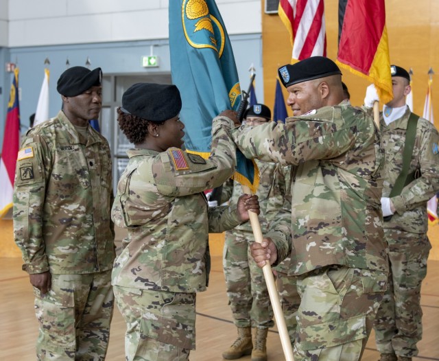 Outgoing Army Field Support Battalion-Mannheim Commander Lt. Col. Brian Astwood passes the battalion colors to the 405th Army Field Support Brigade commander, Col. Crystal Hills, signifying Astwood’s relinquishment of command during a ceremony at Coleman Army Prepositioned Stocks-2 worksite in Mannheim, Germany, June 26. (photo by Elisabeth Paqué, Training Support Center Kaiserslautern) 