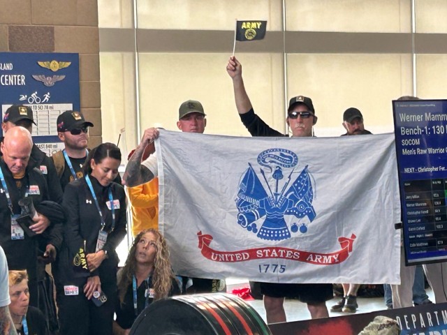 Staff Sgt. Robert Ellison cheers on his teammates while holding the U.S. Army flag during the first day of competition of the DOD Warrior Games Challenge at Naval Air Station North Island, California. 