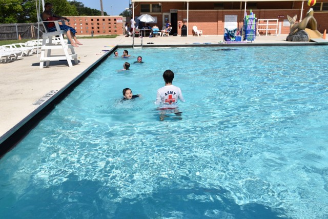 A lifeguard guides young swimmers as they doggy paddle along the edge of the pool during swim lessons June 26, 2023, at Patton Pool on Fort Cavazos. (U.S. Army photo by Janecze Wright, Fort Cavazos Public Affairs)