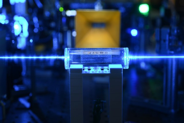 Atoms in a glass vapor cell are excited with laser beams to Rydberg states. They detect the electric fields (coming from the gold antenna in the background) and imprint the information back onto the l