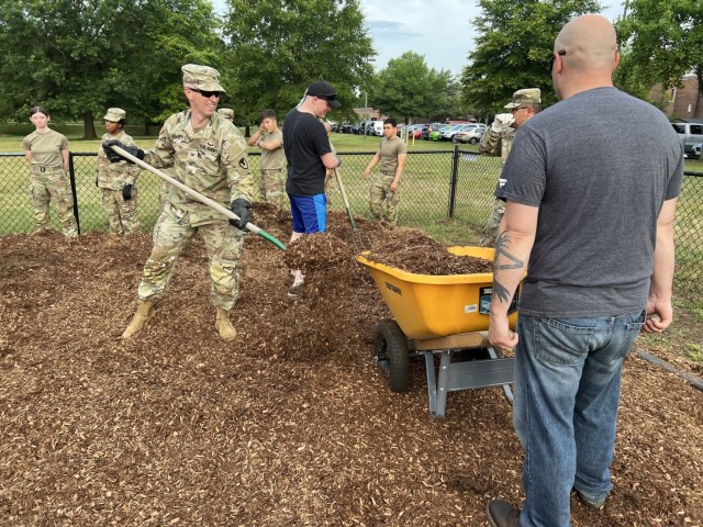 Col. Michael Sapp, garrison commander, pitch-in spreading mulch to restore KABOOM playground.