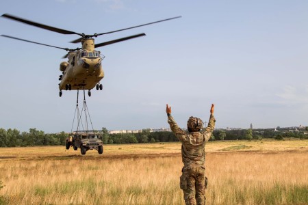 A Soldier assigned to the 1st Squadron, 32nd Cavalry Regiment, 1st Brigade Combat Team, 101st Airborne Division, guides a CH-47 Chinook assigned to the 3rd Combat Aviation Brigade, supporting the 4th Infantry Division, during sling load training at Camp Croft, Hungary, June 23, 2023.