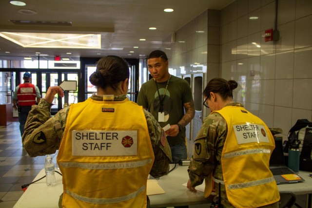 Pvt. Evan Hayles, an evacuated role player with III Armored Corps, speaks with two of the shelter staff during his check-in July 11 at Abrams Physical Fitness Center, which was deemed as the evacuation site for the full-scale exercise that Fort...