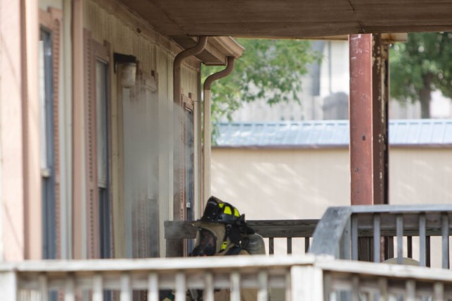 Smoke begins pouring out of a home on the installation, while a fireman readies to enter; the fire began as a result of a simulation two-vehicle accident during a full-scale exercise July 11 on Fort Cavazos. (U.S. Army photo by Scott Darling, Fort Cavazos Public Affairs)