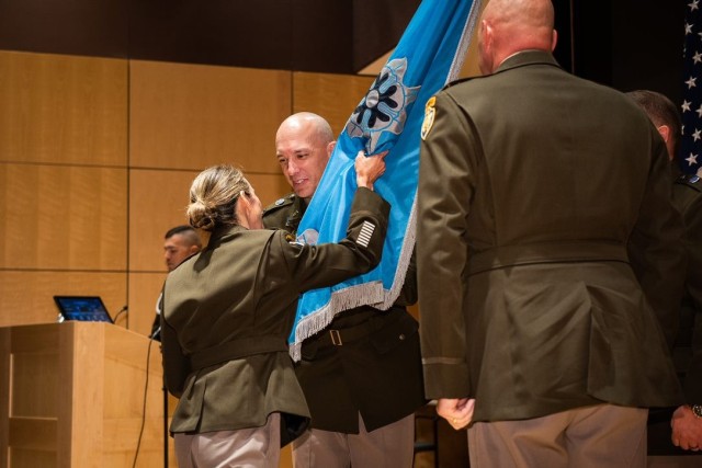 From left, Maj. Gen. Michele H. Bredenkamp, INSCOM commanding general, hands the colors to Col. Eric Haas, incoming commander of the National Ground Intelligence Center, as Col. Christopher Rankin, outgoing commander stands at attention.