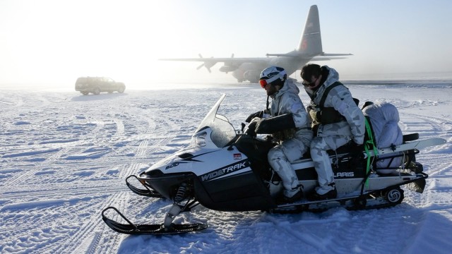 Green Berets assigned to 10th Special Forces Group (Airborne) use a snowmobile to exit the tarmac after loading equipment on a U.S. Air Force C-130 Hercules with the 731st Airlift Squadron for movement north of the Arctic Circle in support of Exercise Arctic Edge 2022 at Fairbanks International Airport, Fairbanks, Alaska, March 2, 2022. 