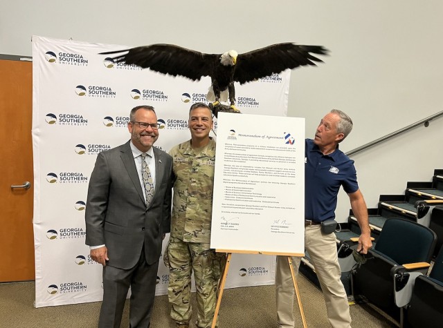Georgia Southern President, Kyle Marrero (left) and Fort Stewart-Hunter Army Airfield Garrison Commander Col. Manny Ramirez (center) pose for a photo next to a signed Memorandum of Agreement, July 31 at the SFC Paul R. Smith Education Center on Fort Stewart. Georgia Southern&#39;s live Bald Eagle mascot &#34;Freedom&#34; and his falconer Steve Hein (right) were also on hand to add to the celebration from above. The MOA signing served as the official announcement of the partnership between Fort Stewart and GSU to offer a series of tailored graduate programs for Soldiers and their dependents.