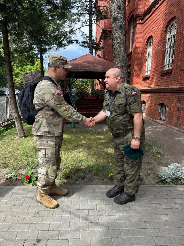 Lt. Col. Michael Kwon (left), Public Health Command Europe Chief of Environmental Health Engineering, gives a coin to Lt. Col. Cezary Gronkiewicz (right), Military Sanitary Inspector at the Military P