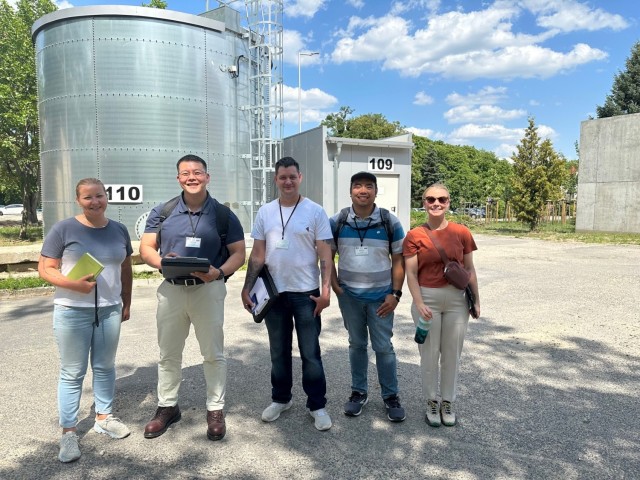 Public Health Command Europe’s Environmental Health Engineering Team and Agnieszka Brown (left), an environmental engineer from Directorate of Public Works-Poland, pose before one of the fire suppress