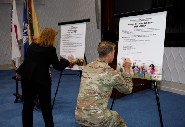 Col. Marcus Hunter, right, commander of U.S. Army Garrison Japan, and Jenifer L. Peterson, deputy garrison commander, sign two pledges in support of U.S. Army Installation Management Command’s Service Culture Initiative during a workforce town hall at Kizuna Hall on Camp Zama, Japan, Aug. 8, 2023.