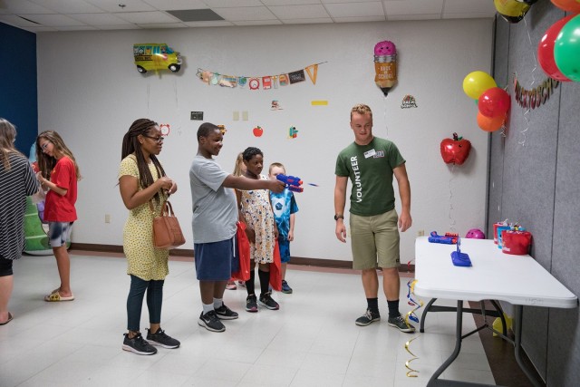 A family participates in one of the carnival-style games Aug. 5. (U.S. Army photo by Blair Dupre, Fort Cavazos Public Affairs)