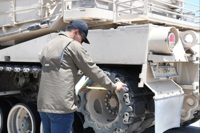 Combat and Automotive Systems Division intern Richard Santiago performs an inspection on the track and sprocket of an Abrams M1A2 SEPv3.