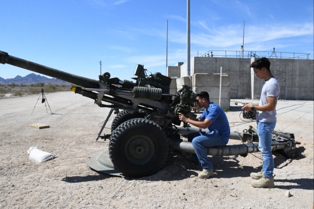 Munitions and Weapons Division interns Dorian Noriega and Gabriel Sepulveda were on site of a test for the M119A3 digital fire control system. Noriega looks through the optical sights to view the line of fire and impact.