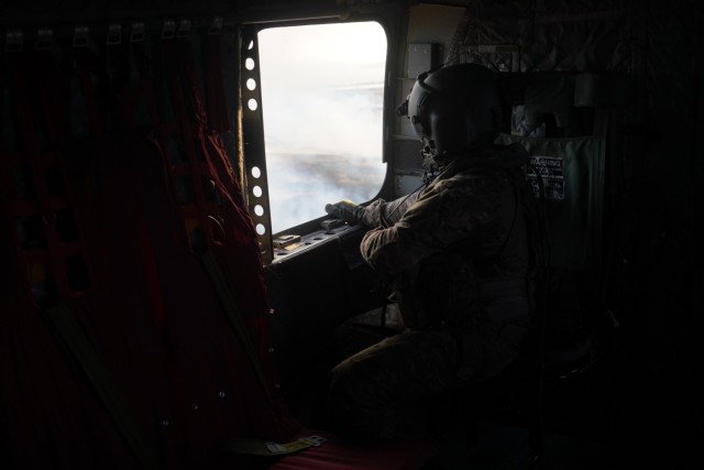 A service member looks out the window of a military aircraft during aerial water bucket drops to fight wildfires in Maui, Hawaii, August 9, 2023.