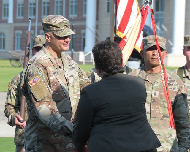 U.S. Army Installation Management Command Directorate Readiness Director Brenda Lee McCollough presents new Fort Stewart Garrison Commander Col. Marc Austin the installation&#39;s color during the change of command ceremony Aug. 11 at Fort Stewart&#39;s Cashe Garden.