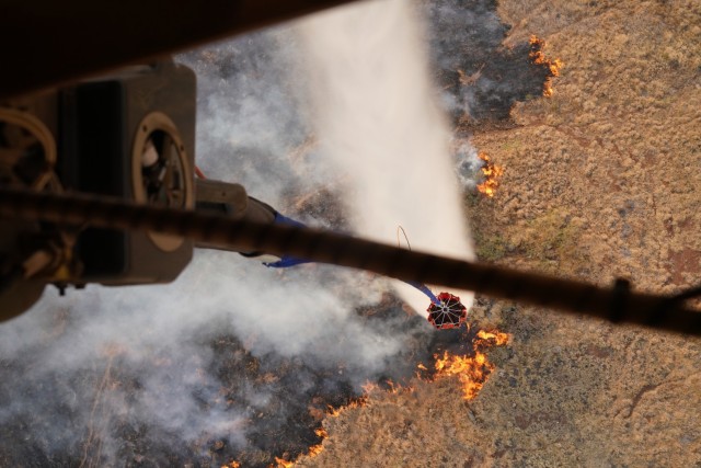 A Hawaii Army National Guard CH47 Chinook participates in an aerial water bucket drop to fight a wildfire on the island of Maui, Hawaii, August 9, 2023.