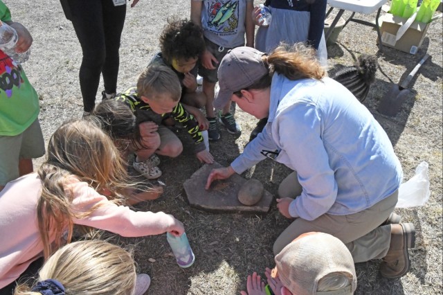 In celebration of Earth Day 2023, U.S. Army Yuma Proving Ground Archeologist Jane Poss (right) showed Price Elementary School students how people used stones to crush seeds from trees to make fine powder. They each had a turn grinding the stones...
