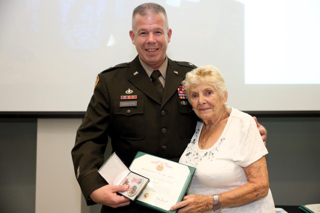 Brig. Gen. Michael J. Simmering, U.S. Army Armor School Commandant, Maneuver Center of Excellence, presents Eva Aiken the Meritorious Public Service Medal for her contributions as a community ambassador to the International Military Students Office during an appreciation dinner at the Cunningham Conference Center in Columbus, Ga., Aug. 15, 2023. The IMSO Ambassador Program is designed to provide hospitality to international military students at Fort Moore and, in some cases, their spouses and children, and provide opportunities for them to become acquainted with American family life. 