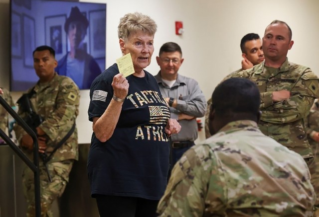 Bonnie Olson, a volunteer with the Fort Cavazos Garrison Chaplain’s Office,  offers prayer cards to Soldiers from the 40th Infantry Division before they depart Larkin Terminal at Robert Gray Army Airfield at Fort Cavazos. (U.S. Army photo by Sgt. 1st Class Justin Hardin, Mobilization Support Brigade)