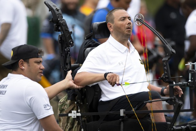 Miguel Avila assists his father Army Capt. Luis Avila with archery in qualifying rounds for the 2023 DoD Warrior Games at Naval Base Coronado in San Diego, Calif. June 8, 2023.