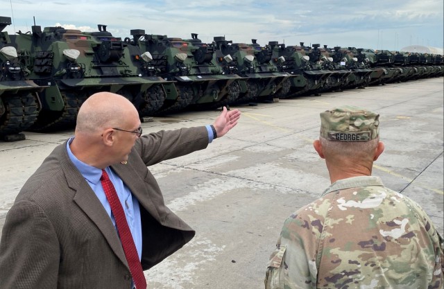 Joseph Scheff, the 405th Army Field Support Brigade deputy to the commander, briefs Vice Chief of Staff of the Army Gen. Randy George in front of a line of Army Prepositioned Stocks-2 armored vehicles at the Coleman APS-2 worksite in Mannheim, Germany, Aug. 25.