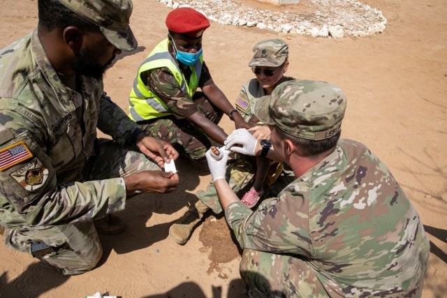 (U.S. Soldiers from the 2nd Security Force Assistance Brigade and a Kenyan Defence Force Soldier assists U.S. Army Lt. Col. Rhonda Dyer , with Civil Affairs East Africa (CA-EA), a forward deployed element of the U.S. Army Southern European Task Force, Africa (SETAF-AF), bandage a burn on a child&#39;s foot during a medical civic action program as part of Justified Accord 23 (JA23) in Larisoro, Kenya on Feb. 19, 2023.)