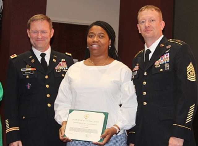 Aviance Oden-Britt, of the Garrison Safety Office, receives an Army certificate of achievement from Garrison Commander Col. Brian Cozine and Command Sgt. Maj. Dylan Lemasters. 