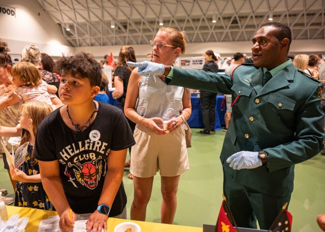 2nd Lt. Misech Kendino, an international student, talks to Anne Gasway, and her son Joseph, about his home country of Papua New Guinea during the 21st Know Your World event, hosted by the International Military Student Office Friday at Nutter Field House. 