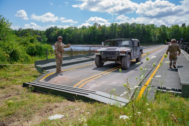 A Connecticut Army National Guard High Mobility Multipurpose Wheeled Vehicle is directed over an improved ribbon bridge by a Connecticut Army National Guard Soldier at Fort Drum, New York, Aug. 11, 2023. Soldiers from the 250th Engineer Company set up the bridge so units of the 143rd Regional Support Group could conduct a wet gap crossing during their annual training.
 (U.S. Army photo by Sgt. Matthew Lucibello)